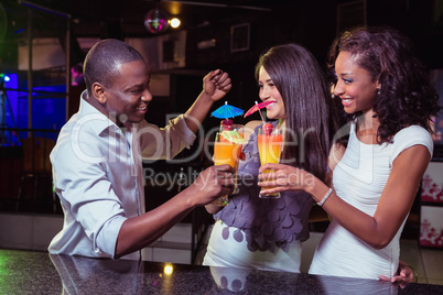 Young friends enjoying while having cocktail drinks at bar count