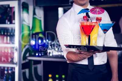 Mid section of bartender serving cocktail and martini