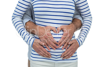 Couple making a heart shape on belly