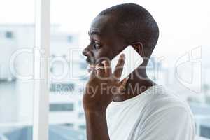 Man talking on mobile phone near window