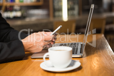 Thoughtful man using laptop and smartphone