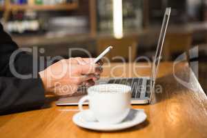 Thoughtful man using laptop and smartphone