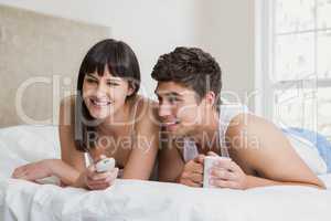 Young couple watching television together on bed
