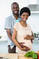 Pregnant couple embracing in kitchen
