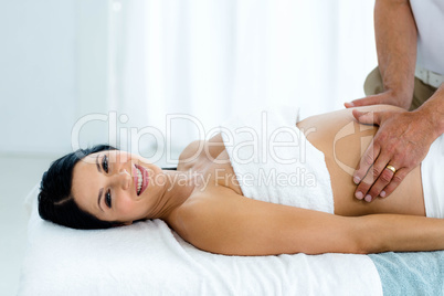 Pregnant woman receiving a stomach massage from masseur