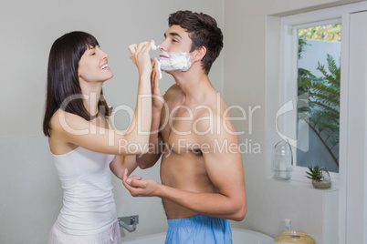 Young woman applying shaving cream on young mans face