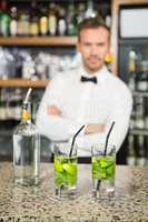 Handsome barman standing behind cocktails