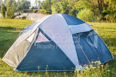 Private camping tent on the meadow near the river.