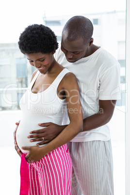 Pregnant couple embracing in bedroom