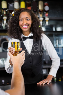 Beautiful barmaid serving beer to man