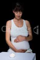 Pregnant woman and glass on table