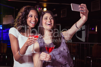 Young women taking a selfie while having a cocktail drink
