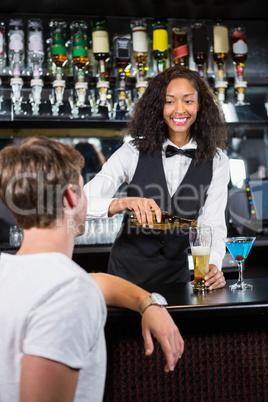 Beautiful barmaid pouring beer in glass