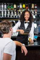 Beautiful barmaid pouring beer in glass