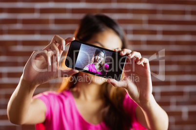 Smiling asian woman taking selfie with smartphone