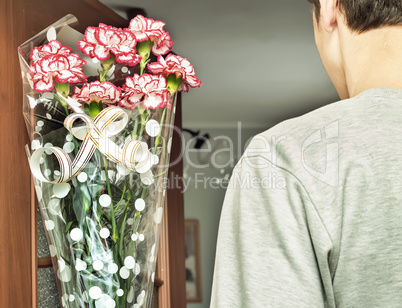 A young man with a bouquet of flowers in his hands.