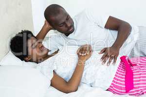 Man touching pregnant womans stomach while relaxing on bed