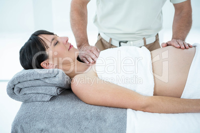 Pregnant woman receiving a stomach massage from masseur