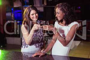 Young women toasting wine glasses at bar counter
