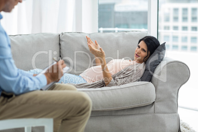 Doctor writing on notepad while consulting pregnant woman