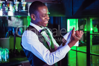 Smiling bartender cleaning a glass