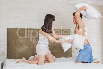 Young couple playing pillow fight