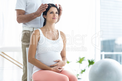 Pregnant woman receiving a head massage from masseur