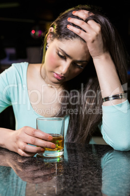 Depressed woman having whiskey at bar counter Depressed woman having whiskey at bar counter