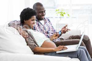 Pregnant couple shopping online on laptop
