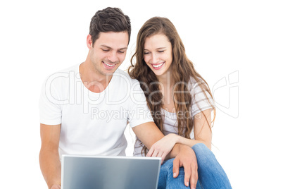 Young couple sitting on floor using laptop