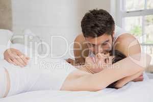 Man kissing woman on bed