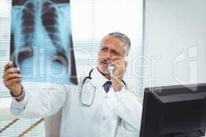 Doctor checking a x-ray report while talking on phone