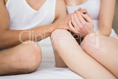 Couple holding hand while sitting on bed