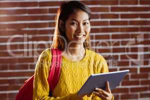 Smiling asian female student using tablet