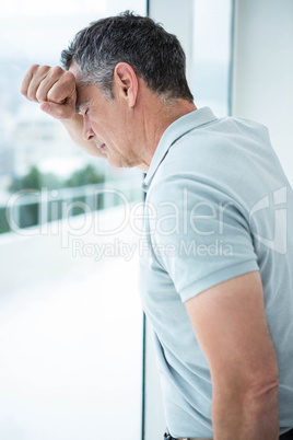 Tensed man leaning on glass window