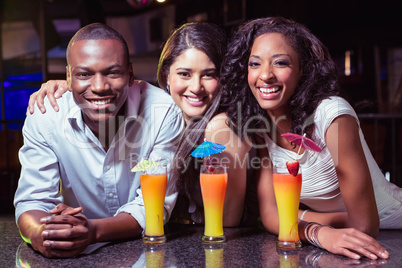 Portrait of friends enjoying while having cocktail drinks at bar