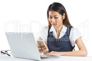 Concentrated businesswoman using smartphone and laptop