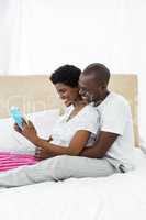 Pregnant couple reading a book on bed