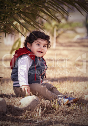 Boy sitting under a palm tree