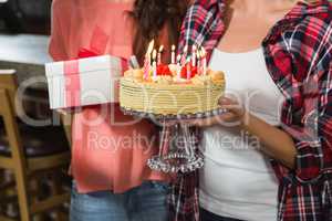 Friends holding a birthday cake and a gift
