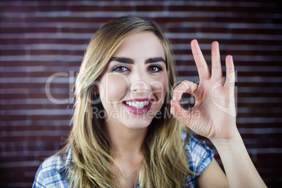 Pretty blonde woman making signs with her fingers