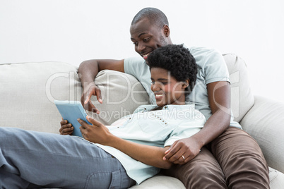 Pregnant couple using digital tablet on sofa