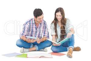 Happy couple studying with books and tablet while sitting on the