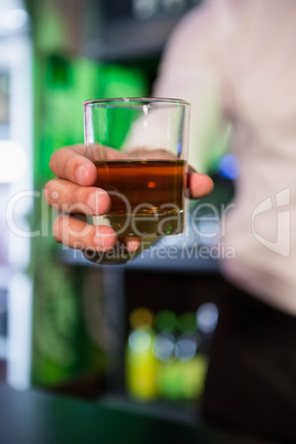 Bartender serving a glass of whiskey