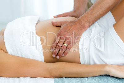 Pregnant woman receiving a stomach massage from masseur