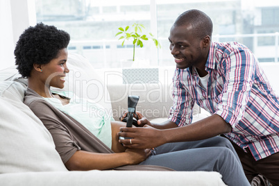 Man holding head phones on pregnant womans stomach
