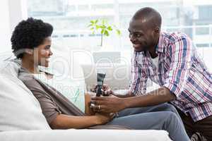 Man holding head phones on pregnant womans stomach