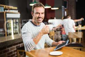 Handsome man using tablet computer and having a coffee