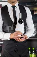 Mid section of bartender holding a wine bottle