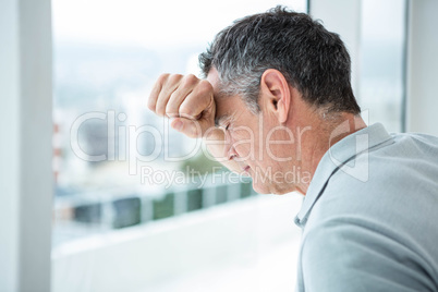 Tensed man leaning on glass window